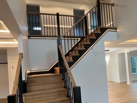 Modern staircase with wood and black railing and lighting