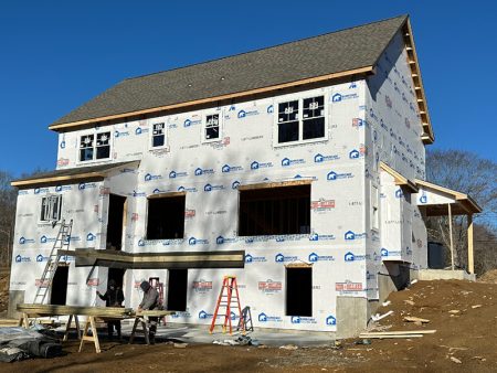 A house under construction with ladders and construction materials outside.