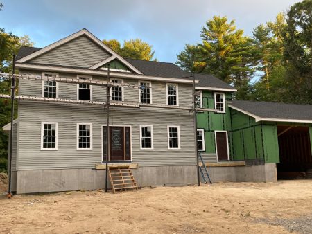 A house under construction with scaffolding and uncompleted siding.
