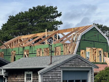 Roof framing under construction with building material and trees